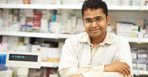 Male pharmacist with his arms folded smiling towards the camera